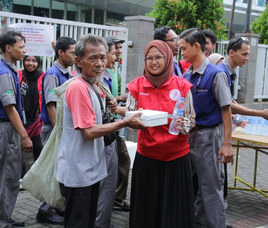 Relawan membagikan nasi kotak dan air minum kepada warga di jalan
