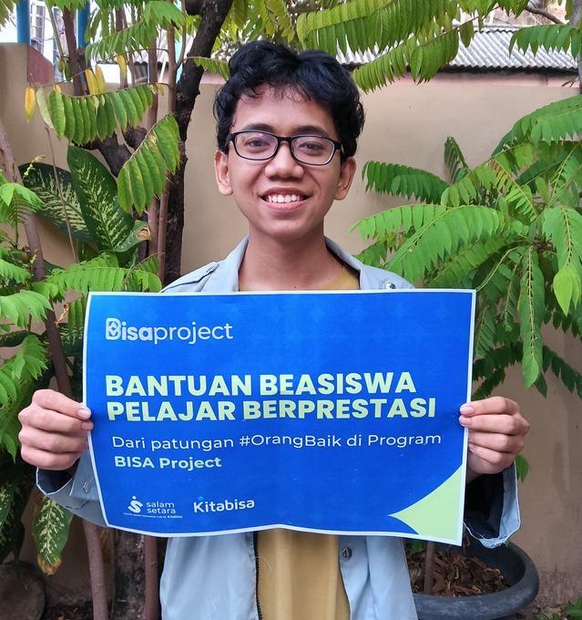 Penerima beasiswa memegang papan Bantuan Beasiswa Pelajar Berprestasi BISA Project