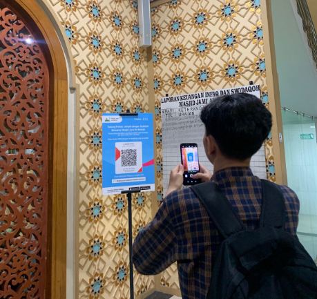 Jamaah memindai QR code donasi digital di pintu masuk masjid