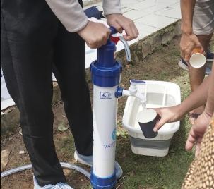 Warga menggunakan filter air minum dengan pompa tangan